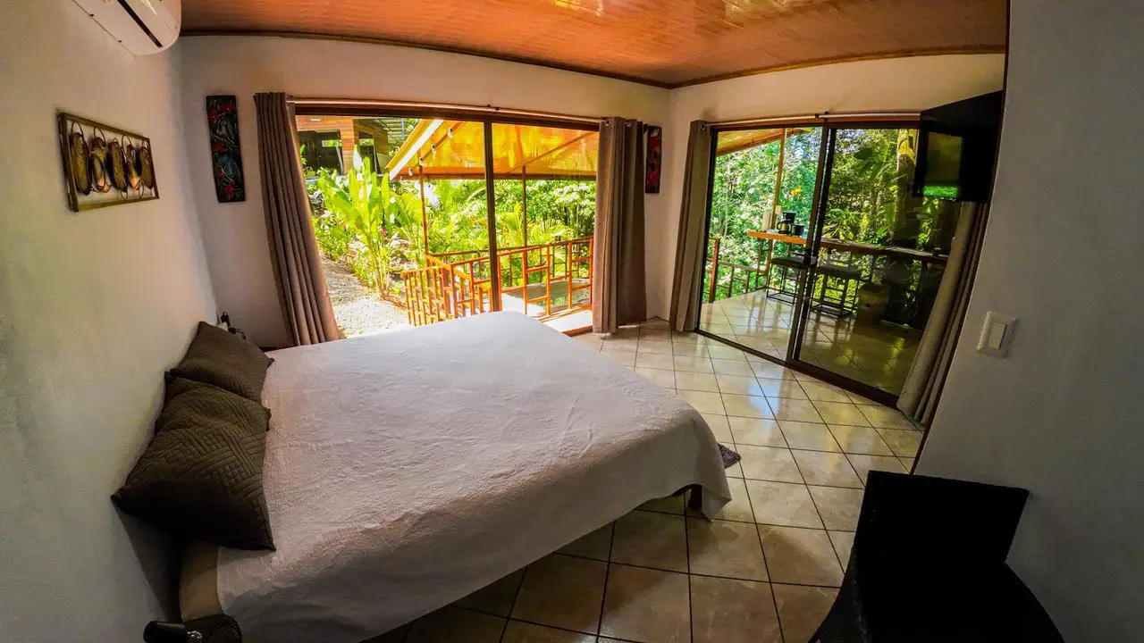 Dormitorio de cabaña turística Airbnb con vista a jardín tropical en La Fortuna